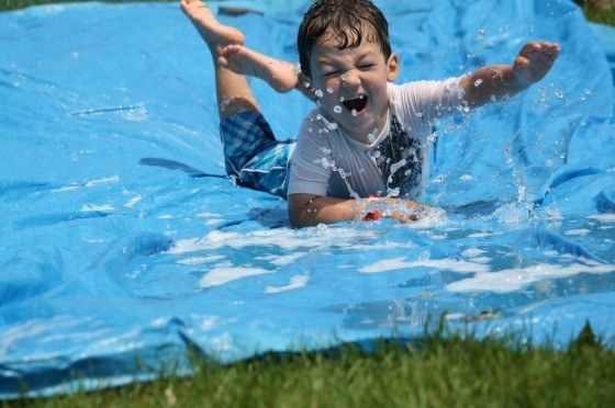 Make an easy water slide using a tarp, a hose, and shampoo.